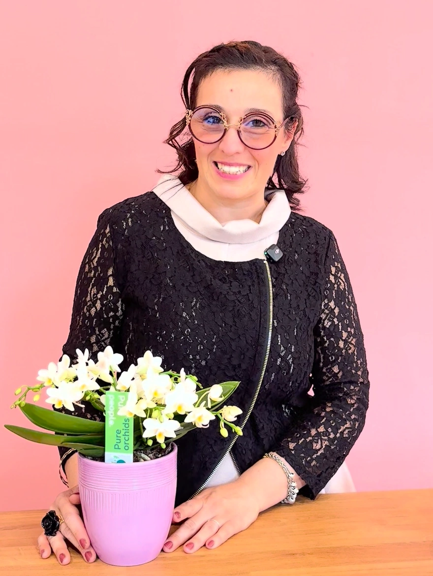 Federica sorride nel suo atelier, accanto a una piccola orchidea fiorita